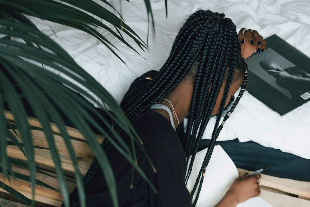 box braids vs cornrows debate. woman with braids writing down content on a notebook