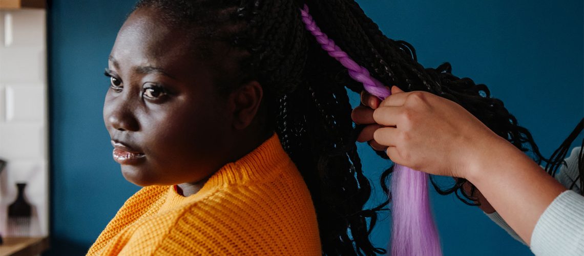 woman getting hair braided, wondering how long do african braids last